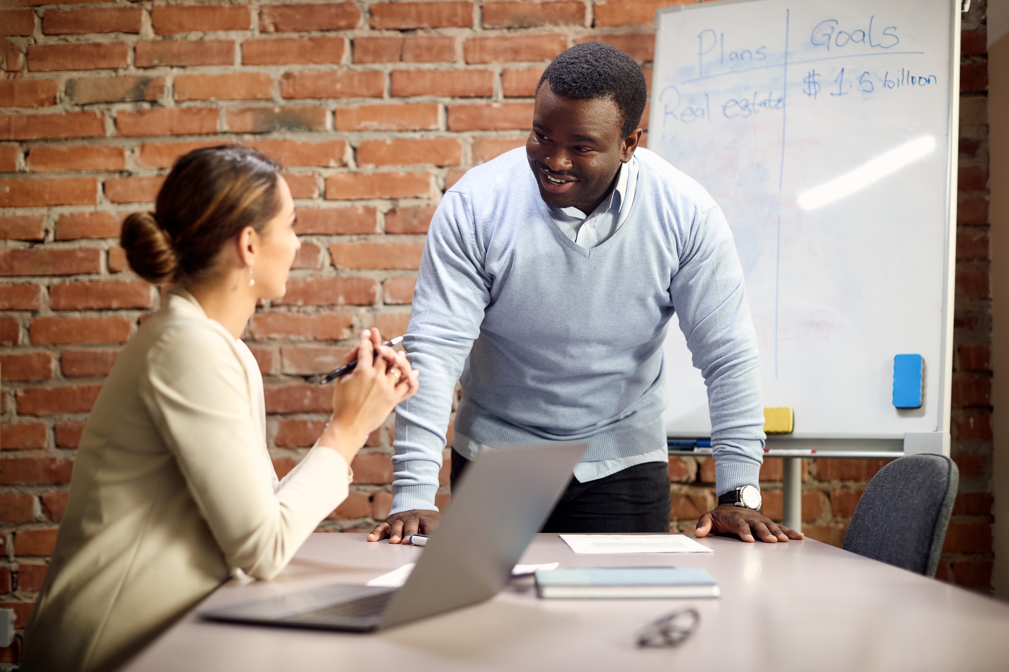 Happy real estate agents talking during their business meeting in the office.